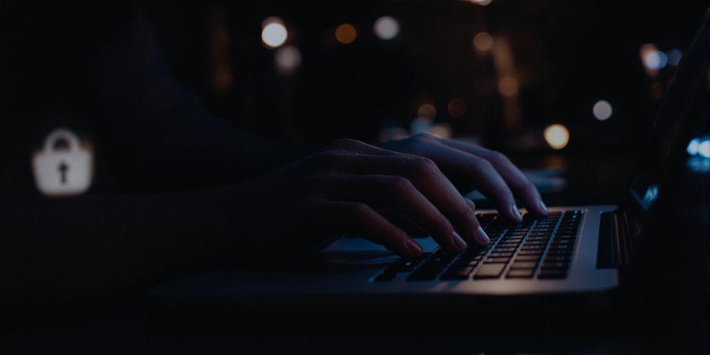 Person typing on laptop in a secure environment.