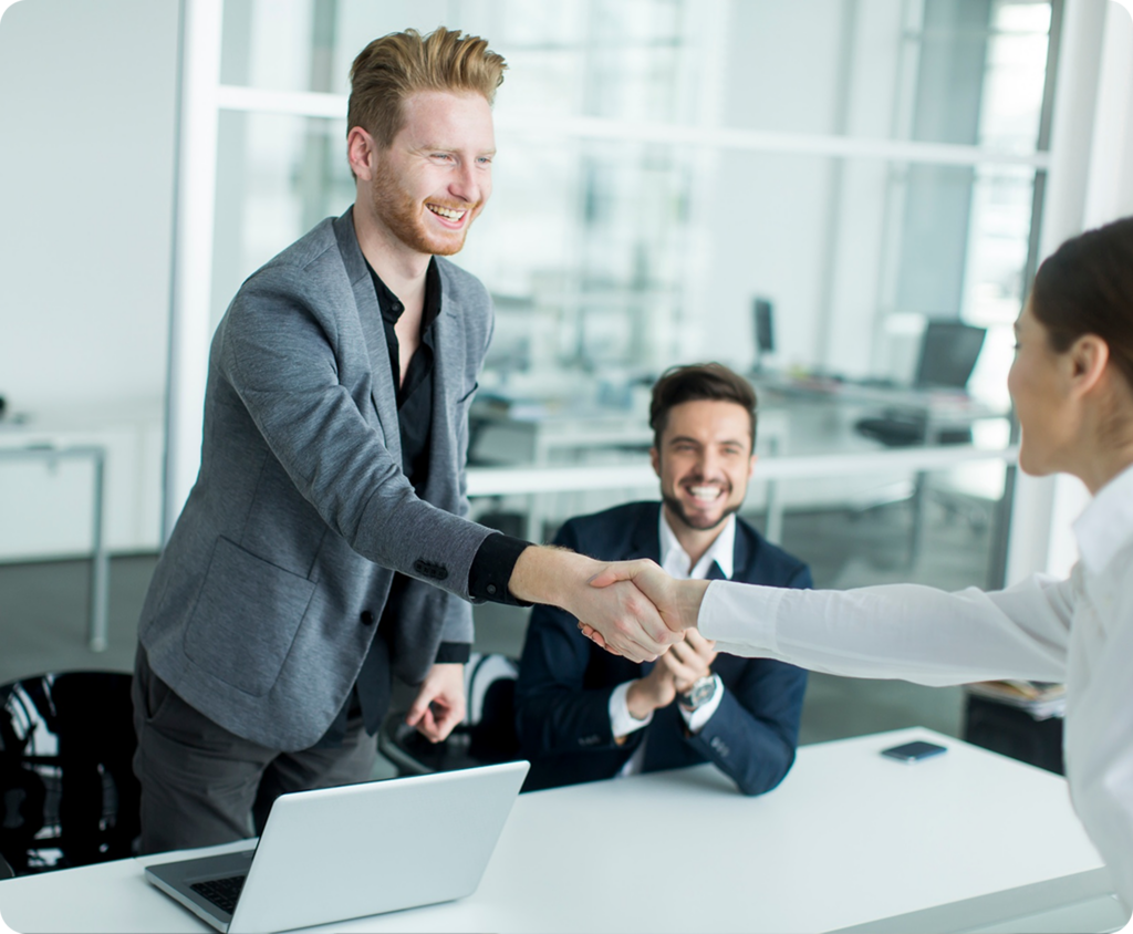 Two business professionals shaking hands across a conference table in a bright modern office, representing Tech Support Austin IT services.